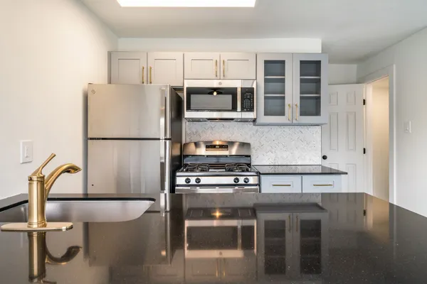 a kitchen with stainless steel appliances granite countertop a stove a refrigerator and a dining table with wooden floor