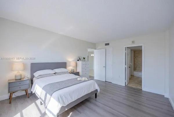 a spacious bedroom with a bed and a lamp