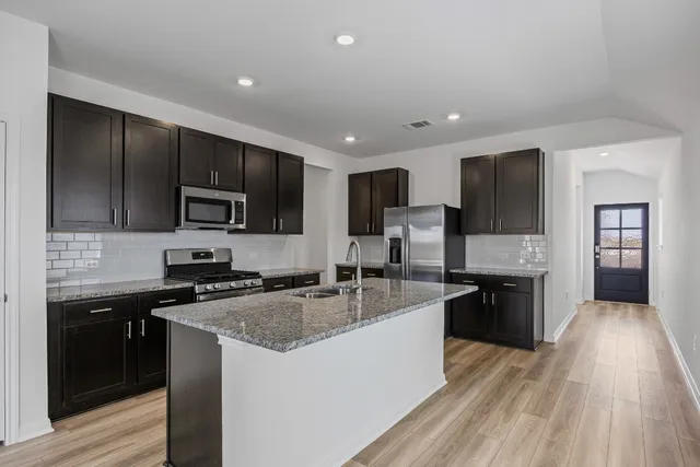 a kitchen with granite countertop a sink counter top space appliances and cabinets