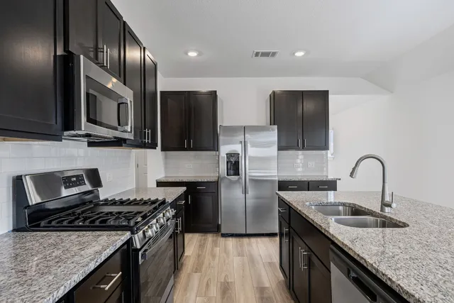 a kitchen with stainless steel appliances granite countertop a sink stove and microwave
