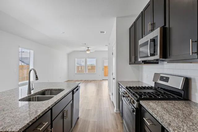 a kitchen with stainless steel appliances granite countertop a stove sink microwave and refrigerator