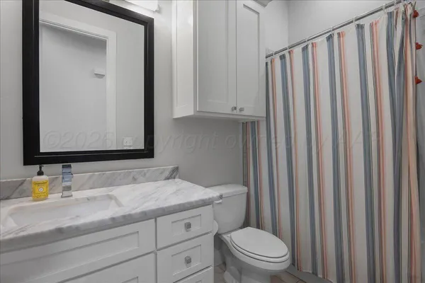 a bathroom with a granite countertop toilet sink and mirror