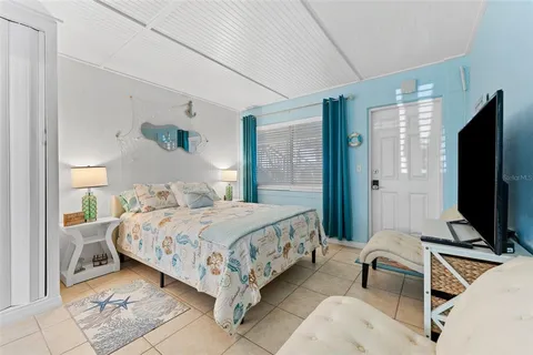 a bedroom with a bed and a flat tv screen on dresser