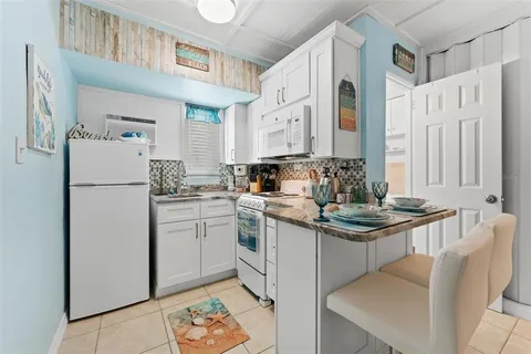a kitchen with stainless steel appliances granite countertop a refrigerator a sink and white cabinets
