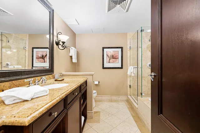 a en suite bathroom with a granite countertop sink and mirror