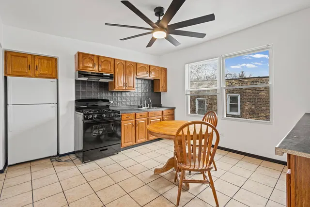 a kitchen with stainless steel appliances granite countertop a stove a refrigerator a sink a dining table and chairs with wooden floor