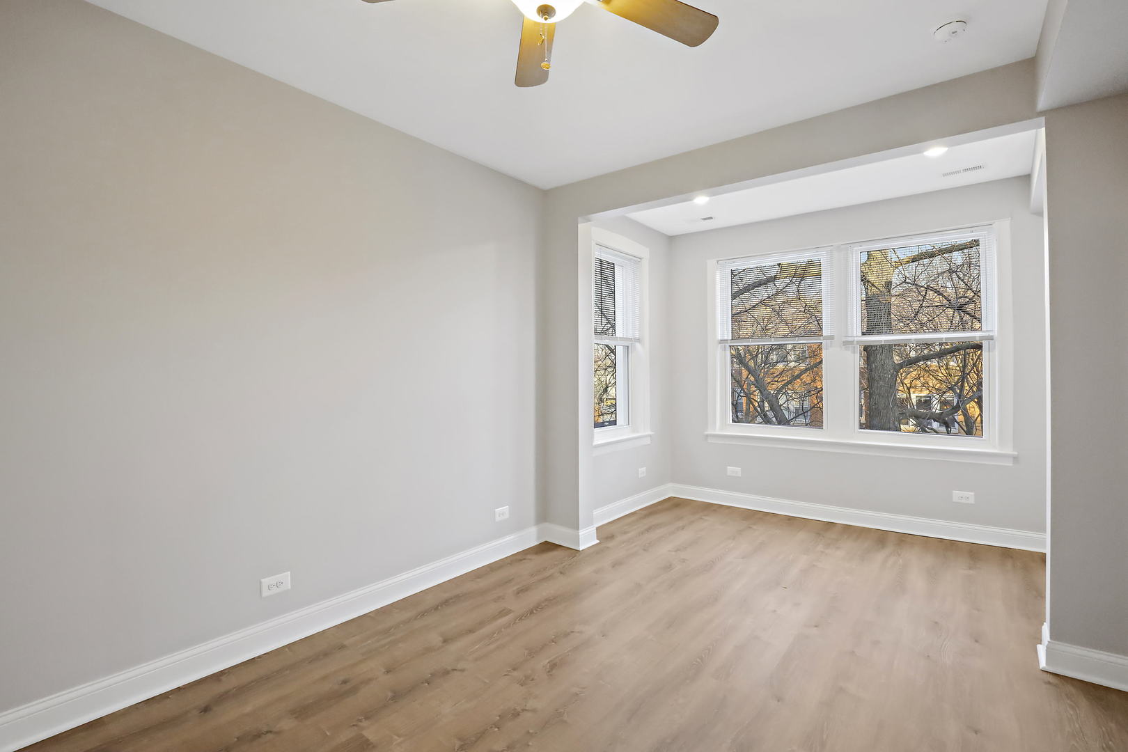 2626 North Ridgeway Avenue, Unit 1 Chicago, IL 60647 - Photo 10 of 16 an empty room with windows and chandelier fan