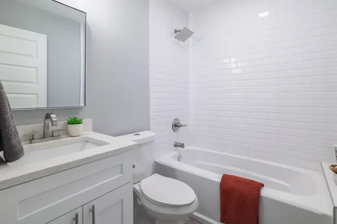a bathroom with a granite countertop sink a toilet and bathtub