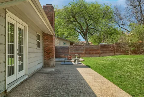 a view of a backyard with wooden fence and a bench