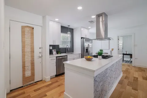a kitchen with stainless steel appliances kitchen island granite countertop a sink a refrigerator and a stove