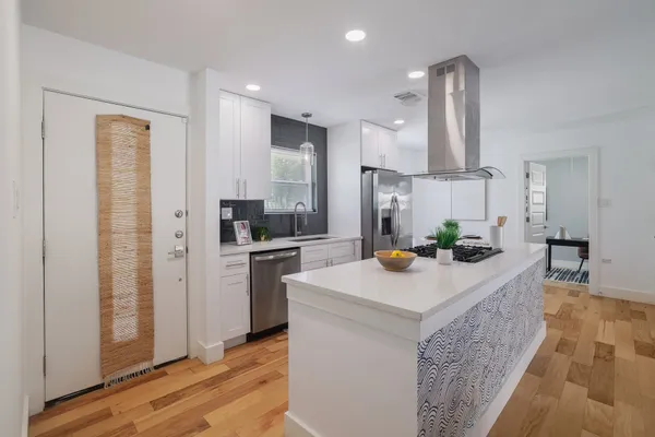 a kitchen with stainless steel appliances kitchen island granite countertop a sink a refrigerator and a stove