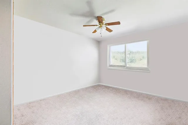 an empty room with a window and ceiling fan