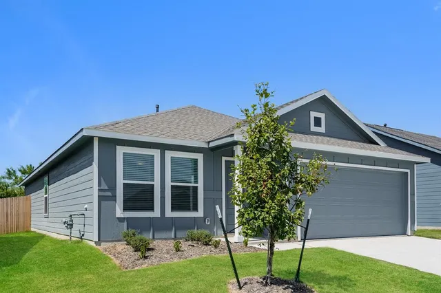 a front view of a house with a yard and trees