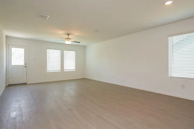 an empty room with windows and chandelier fan