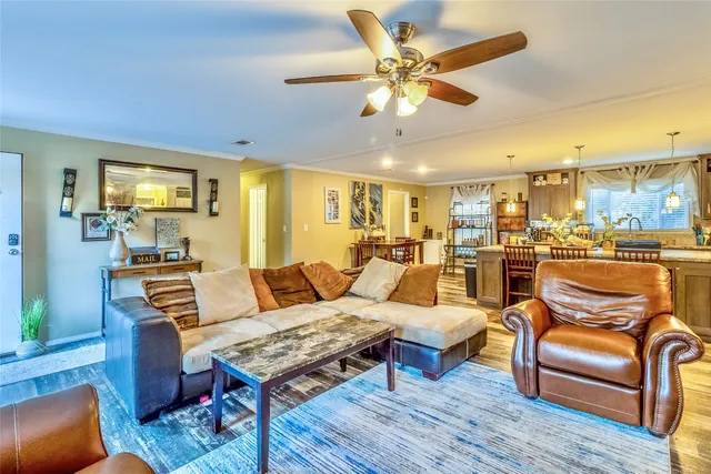 a living room with furniture kitchen view and a wooden floor