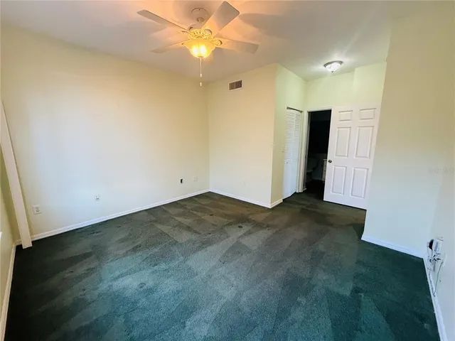 an empty room with a ceiling fan and closet area