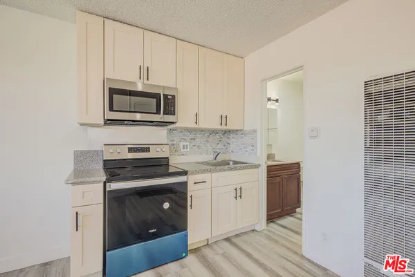 a kitchen with stainless steel appliances granite countertop a stove a microwave and a white cabinets