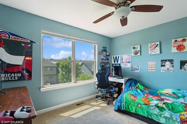 a bedroom that has a bed dresser and paintings on the wall