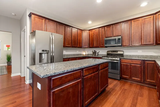 a kitchen with stainless steel appliances granite countertop wooden cabinets a refrigerator and sink