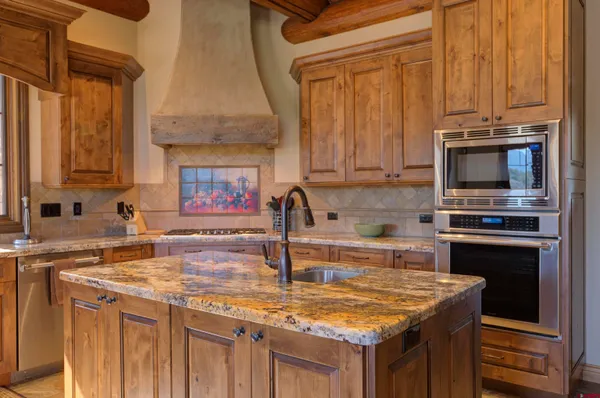 a kitchen with kitchen island granite countertop a sink stove and microwave