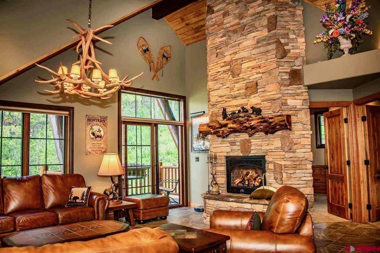 702 Jenni Lane, Unit SADDLEHORN RANCH Chromo, CO 81128 - Photo 38 of 45 a living room with furniture a chandelier and a fireplace