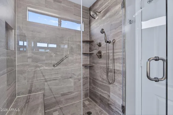 a en suite bathroom with a granite countertop sink a mirror and shower