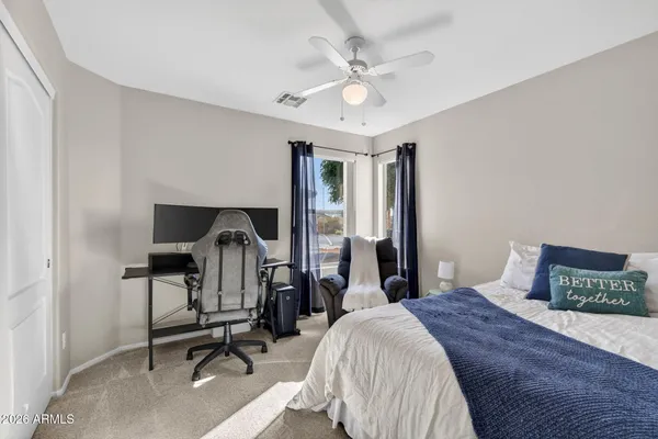 a spacious bedroom with a bed and a flat tv screen on the dresser