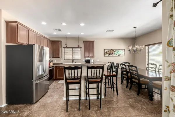 a kitchen with kitchen island a dining table chairs and refrigerator