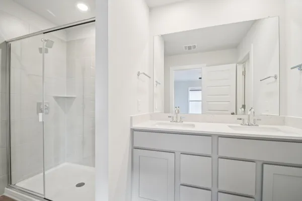 a bathroom with a double vanity sink mirror and shower