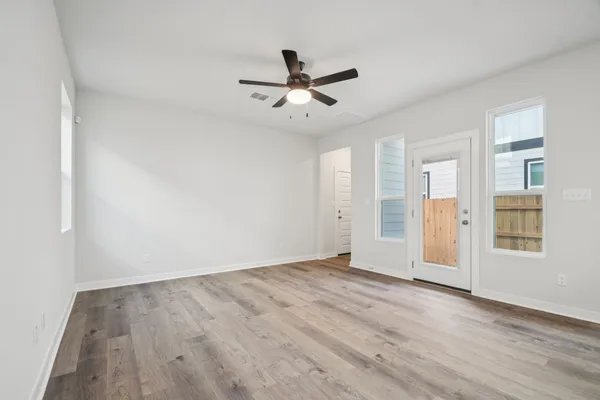 an empty room with wooden floor ceiling fan and windows