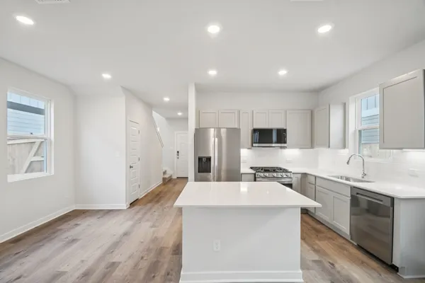 a large kitchen with a large counter top a sink stainless steel appliances and cabinets