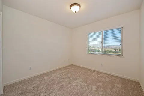 an empty room with windows and chandelier fan