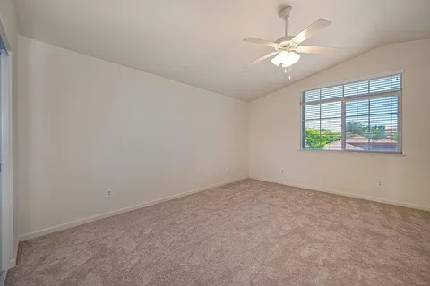 a view of empty room with window and ceiling fan