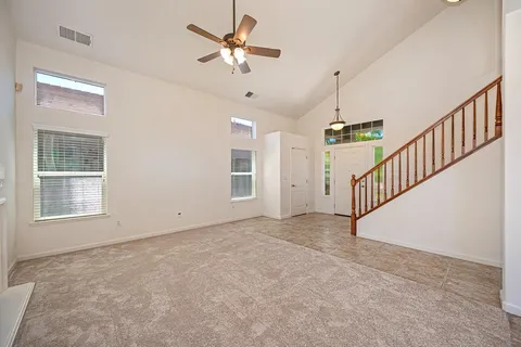 an empty room with windows a fireplace and a chandelier fan