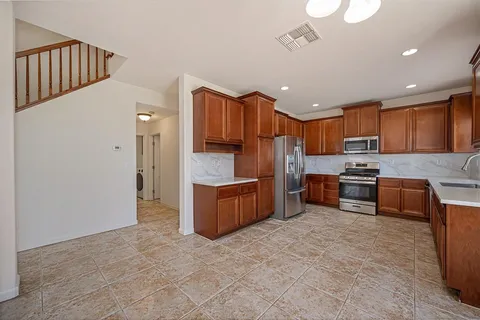 a kitchen with granite countertop a refrigerator stove top oven and sink