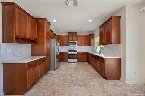 a kitchen with granite countertop wooden cabinets stainless steel appliances and a window