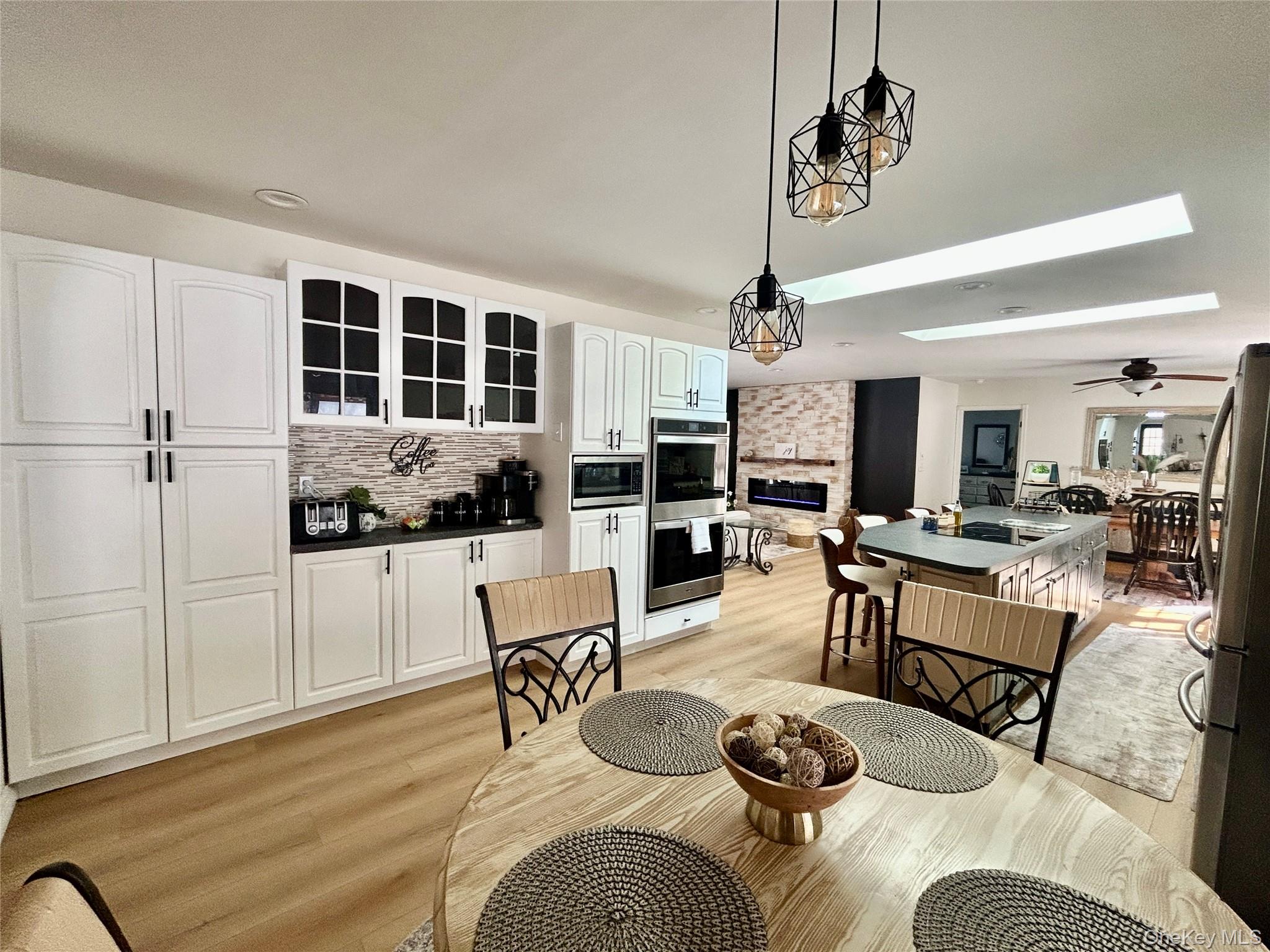 290 Gulf Road Roscoe, NY 12776 - Photo 11 of 26 Dining area with light wood-type flooring, a large fireplace, a ceiling fan, and a skylight