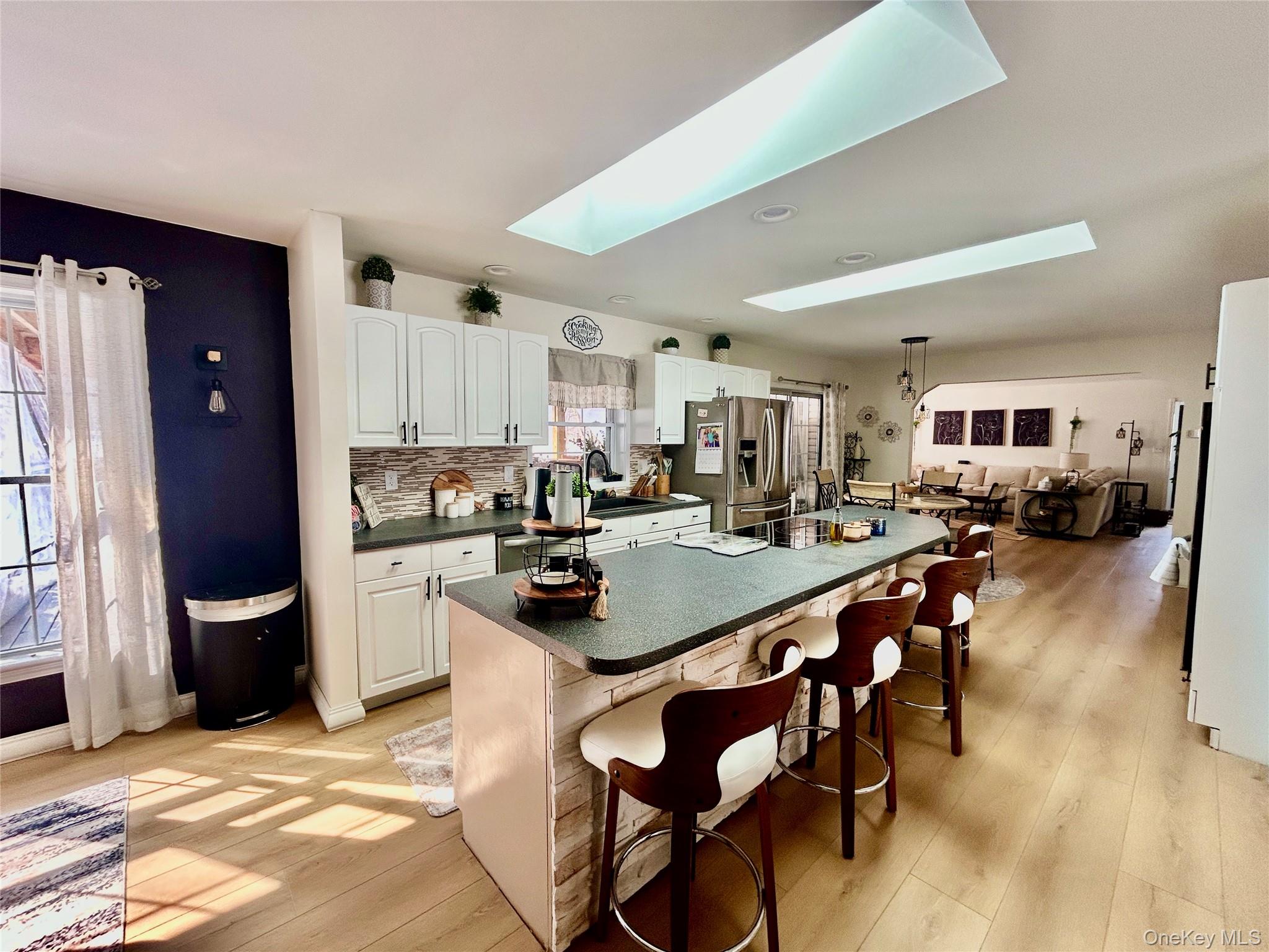 290 Gulf Road Roscoe, NY 12776 - Photo 12 of 26 Kitchen with a skylight, a breakfast bar, dark countertops, stainless steel fridge with ice dispenser, and white cabinets