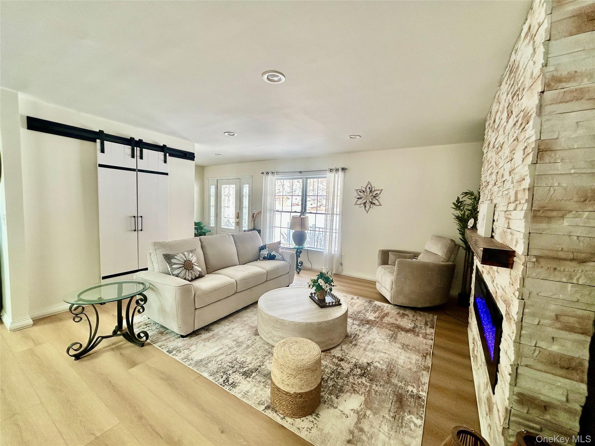 290 Gulf Road Roscoe, NY 12776 - Photo 14 of 26 Living room featuring a barn door, light wood-type flooring, and a stone fireplace