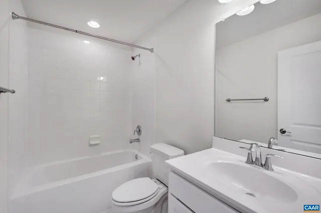 a bathroom with a bathtub shower sink vanity mirror and toilet