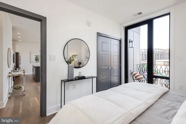 a bedroom with a bed and a large mirror next to a window