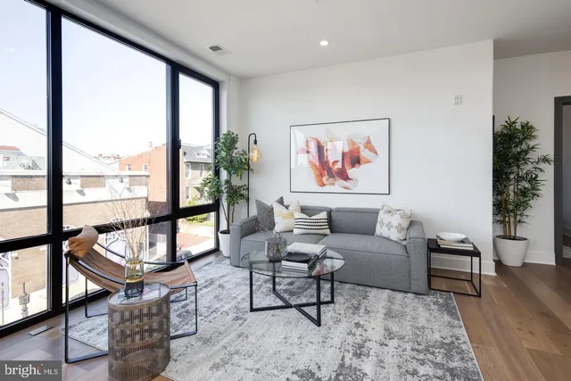 a living room with furniture a rug wooden floor and a large window