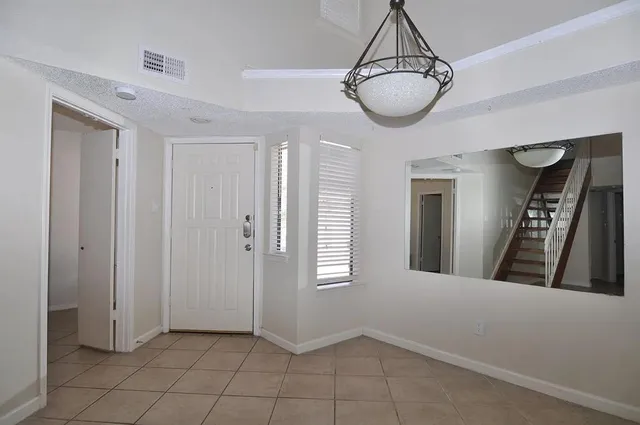 a view of a hallway with two windows and chandelier in a room