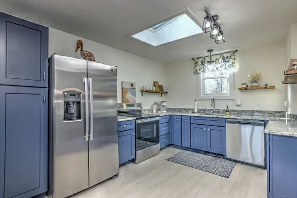 a kitchen with granite countertop stainless steel appliances a sink and a refrigerator