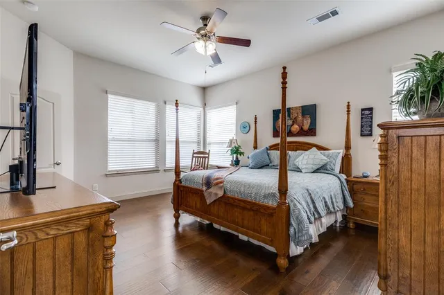 a bedroom with a large bed a flat tv screen and dresser