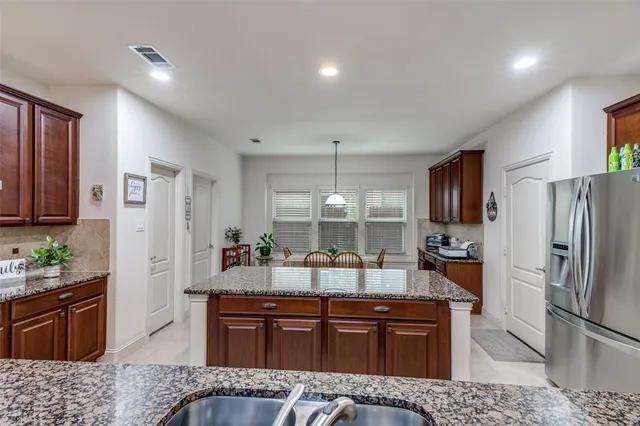 a large kitchen with stainless steel appliances granite countertop a refrigerator a oven a sink dishwasher and wooden cabinets with wooden floor