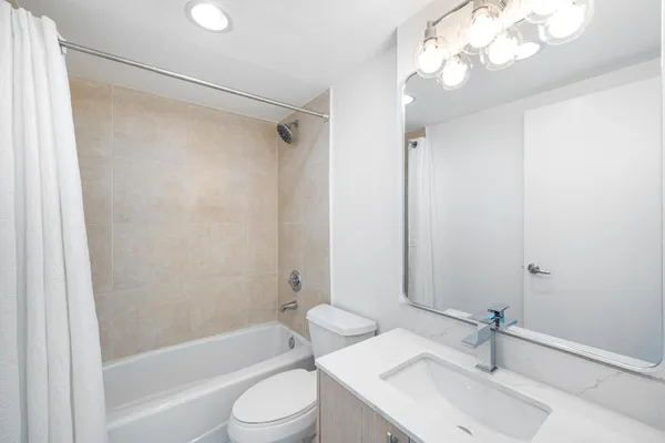 a bathroom with a sink a toilet a mirror and shower