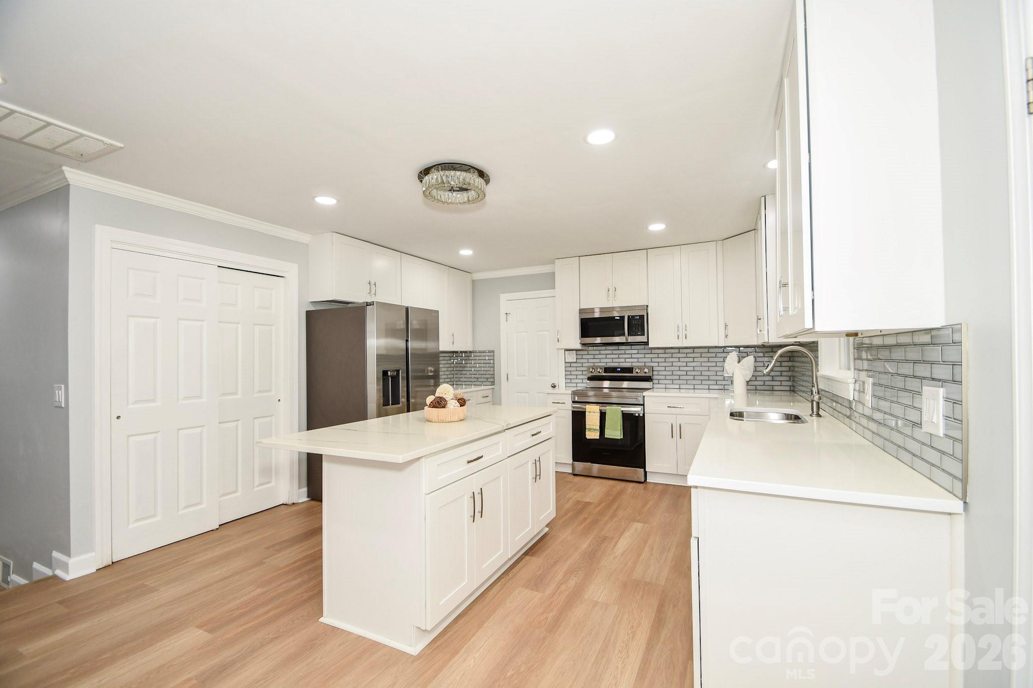 4517 Plyler Mill Road Monroe, NC 28112 - Photo 12 of 37 a kitchen with a sink a stove top oven a refrigerator and white cabinets with wooden floor