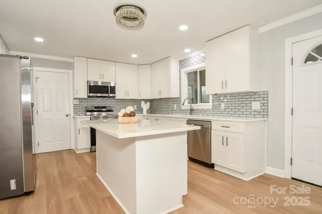a kitchen with kitchen island granite countertop a sink appliances cabinets and a counter top space