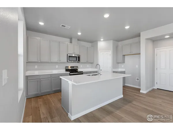 a kitchen with kitchen island sink stove and white cabinets